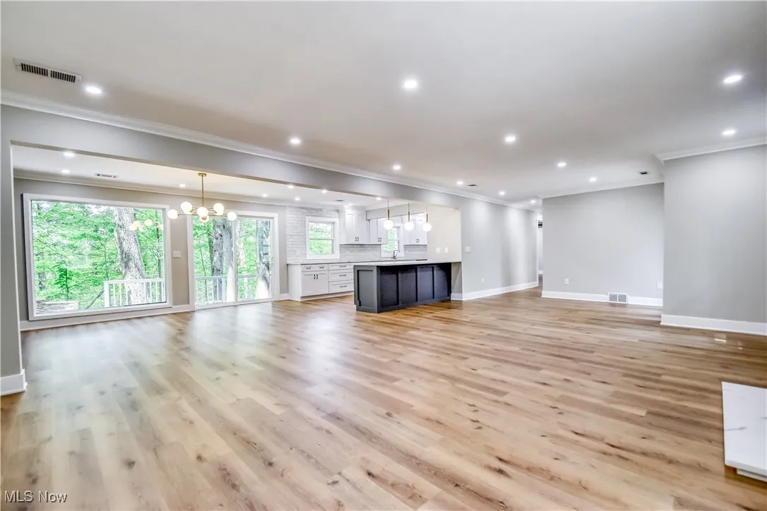 Unfurnished living room with a chandelier, ornamental molding, recessed lighting, and light wood-style floors