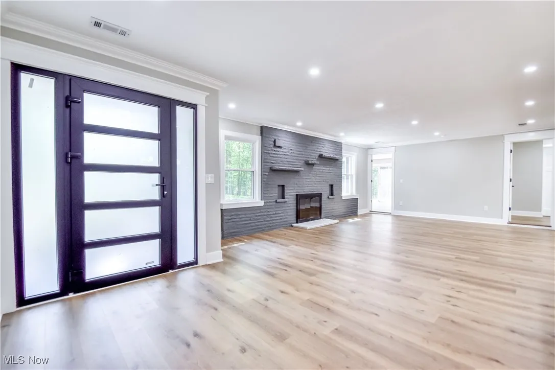 Unfurnished living room featuring ornamental molding, light wood finished floors, a fireplace, and recessed lighting