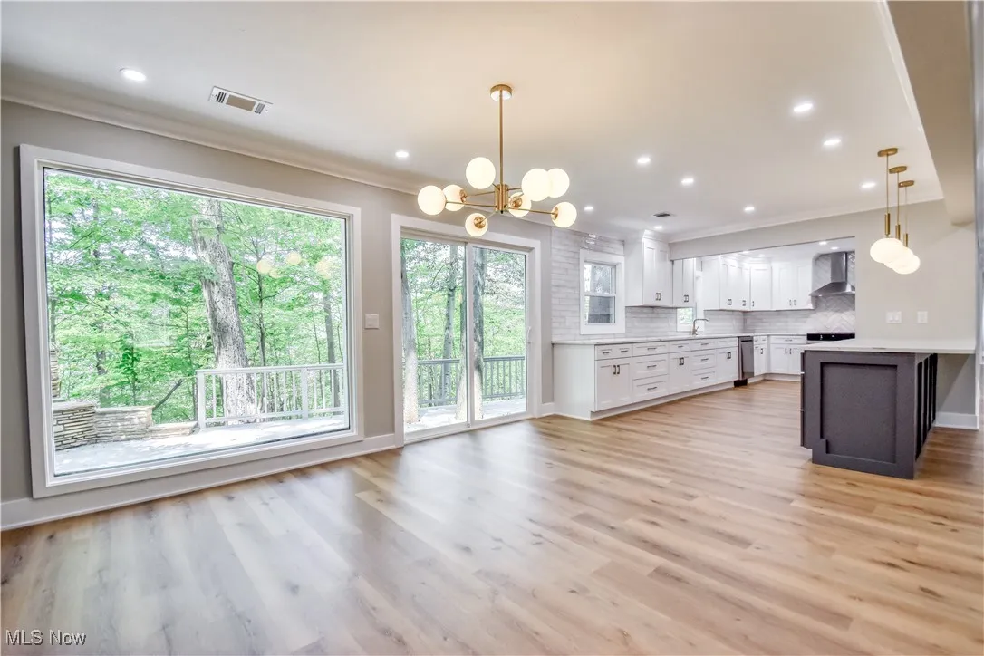 Kitchen with white cabinetry, decorative light fixtures, tasteful backsplash, a chandelier, and ornamental molding