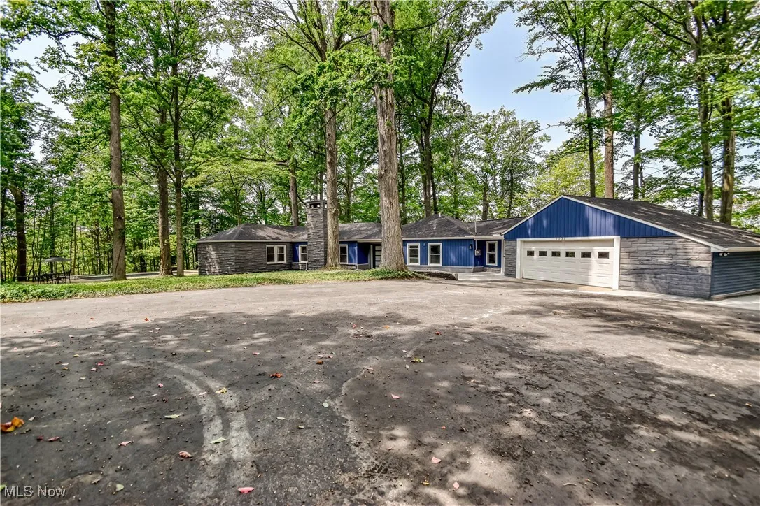 View of front of house with view of wooded area, a chimney, and an attached garage