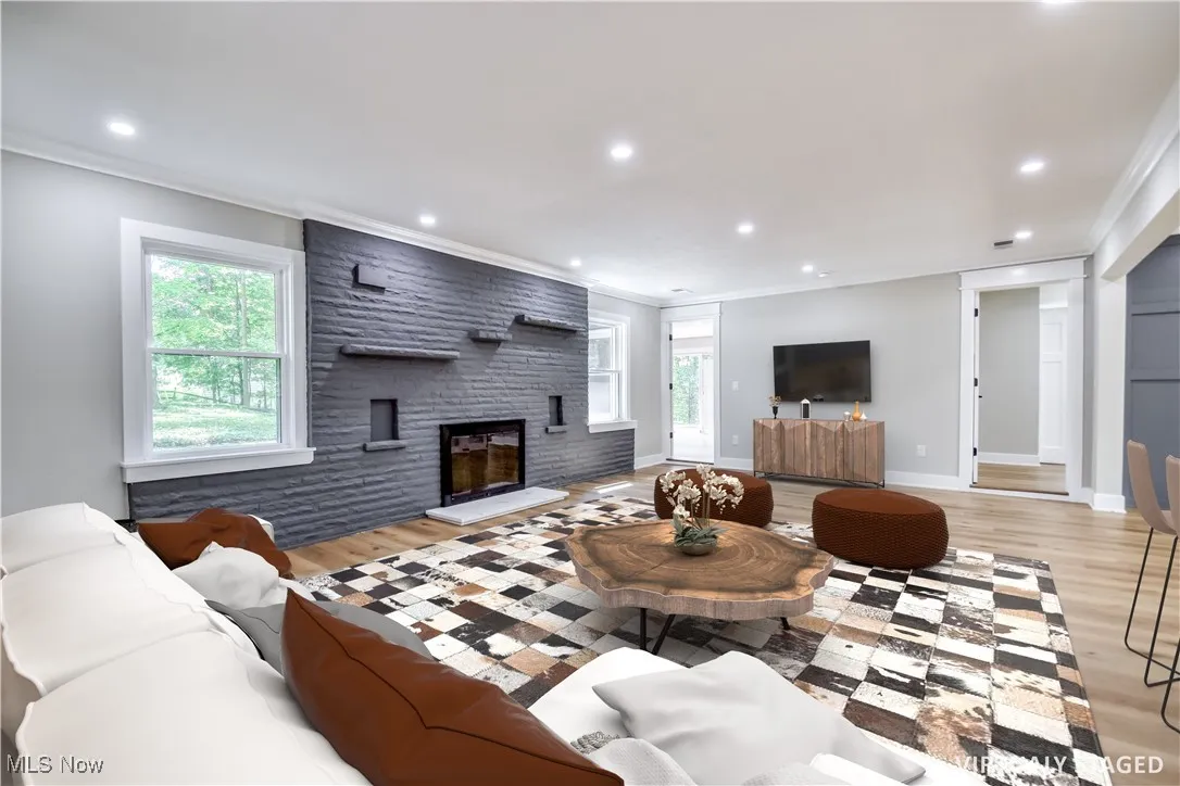 Living room with crown molding, light wood finished floors, recessed lighting, and a fireplace