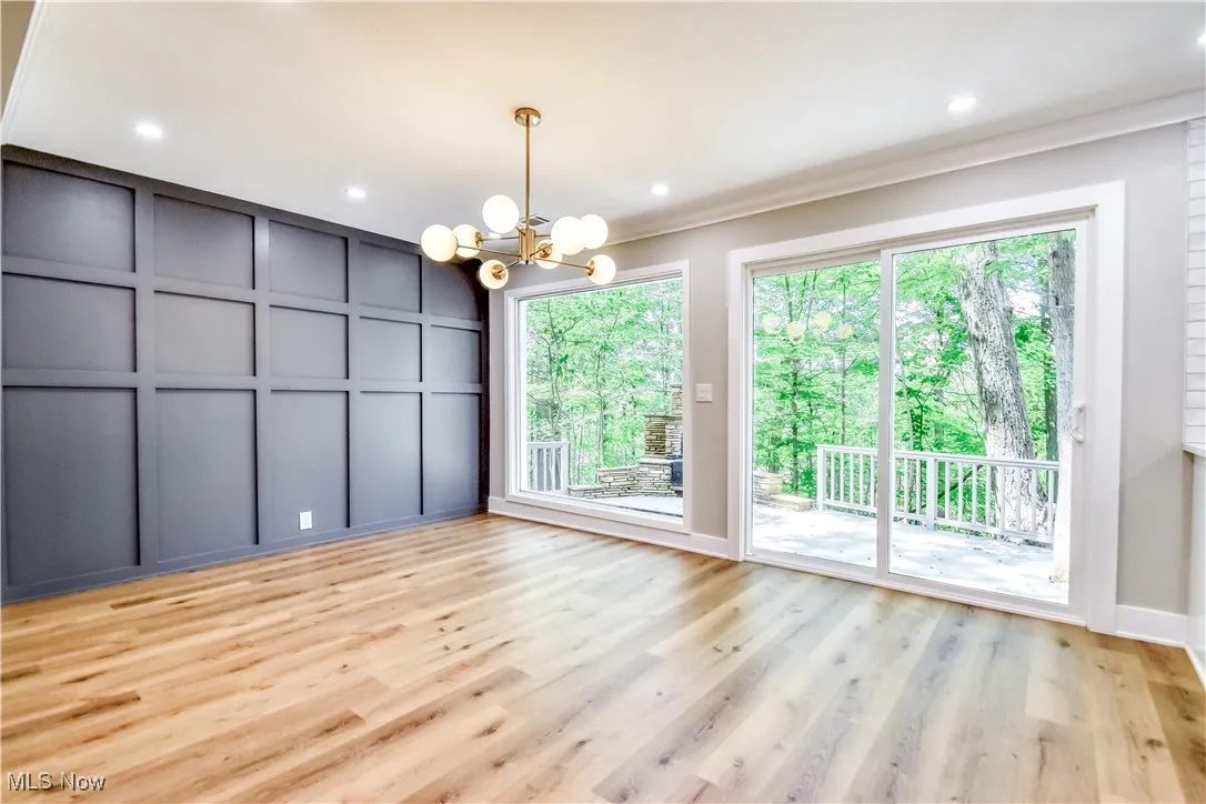 Unfurnished dining area with a decorative wall, a chandelier, light wood-style flooring, recessed lighting, and ornamental molding