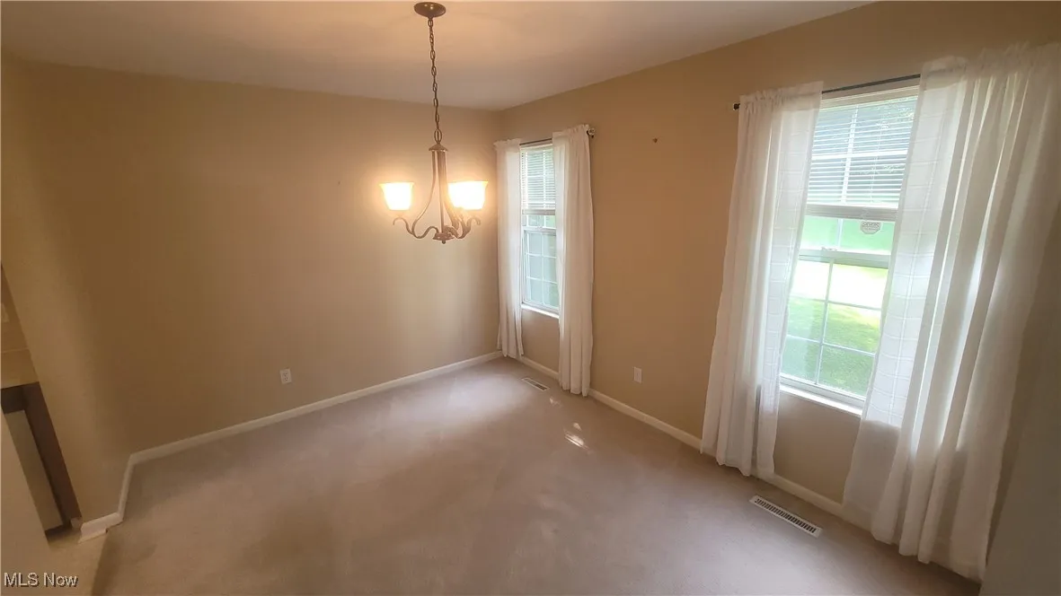 Unfurnished dining area with carpet flooring and a chandelier