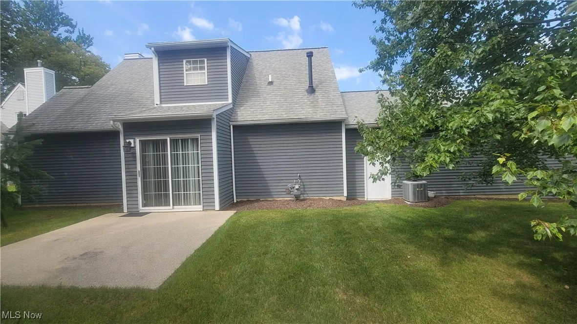 Back of property featuring roof with shingles and a yard