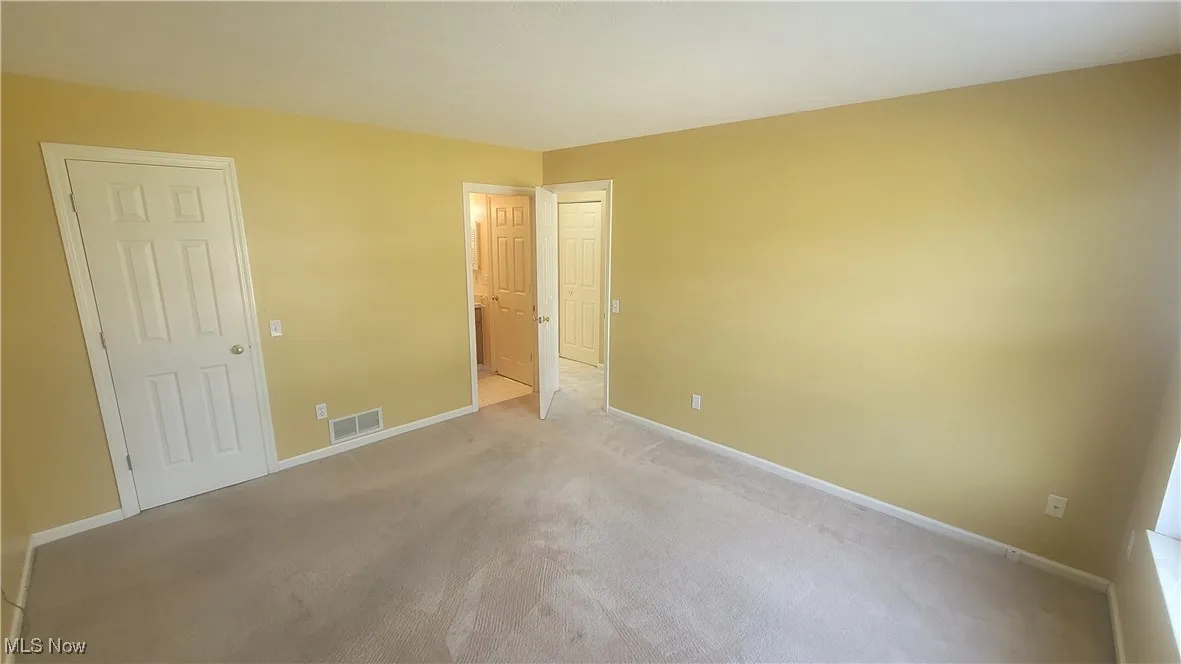 Unfurnished bedroom featuring carpet, walk in closet, and access to bathroom.