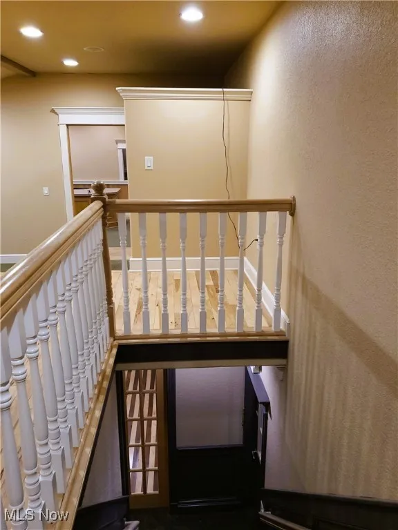 Staircase featuring a textured wall and recessed lighting