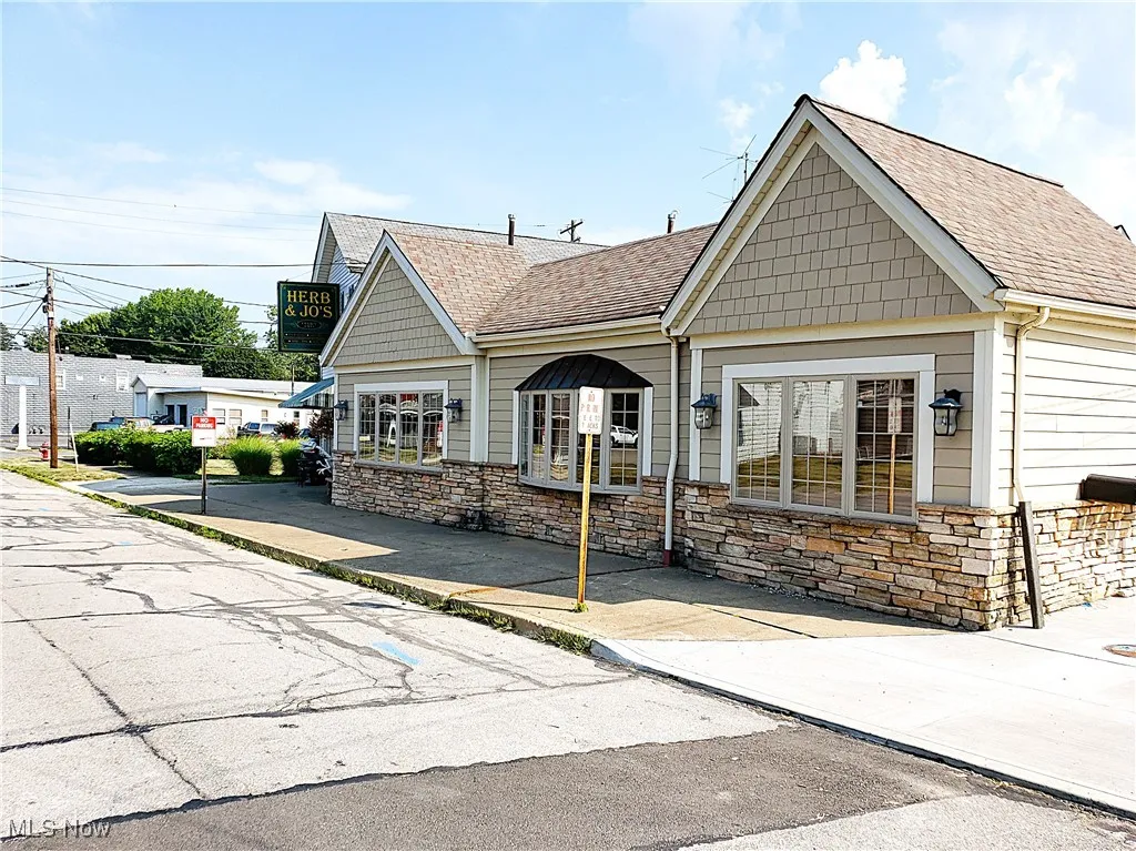 View of front of property featuring a shingled roof and stone siding