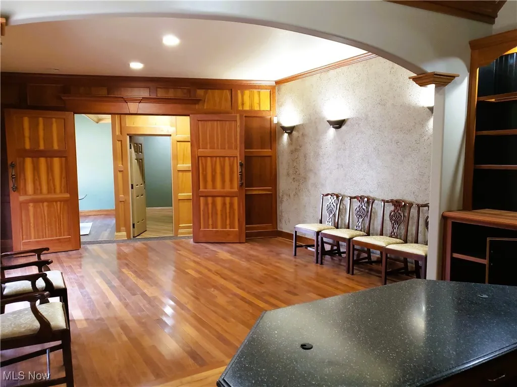 Sitting room featuring arched walkways, crown molding, light wood-style flooring, and recessed lighting