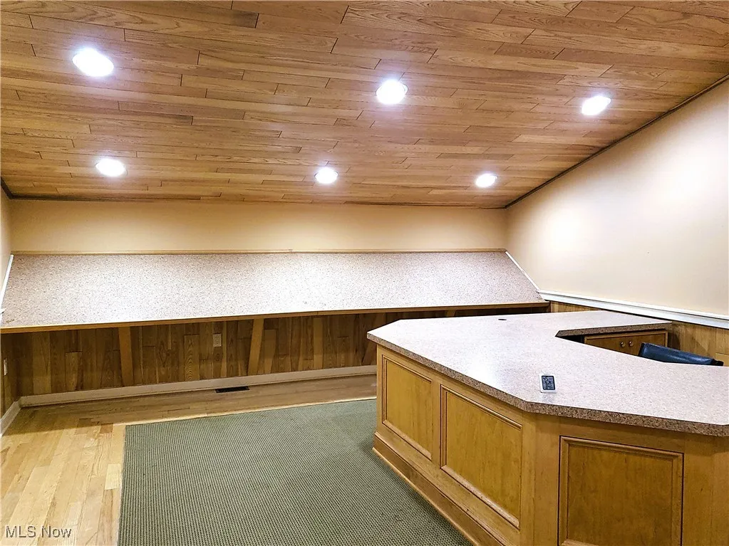 Unfurnished office with wood ceiling, wainscoting, light wood-style floors, recessed lighting, and wood walls