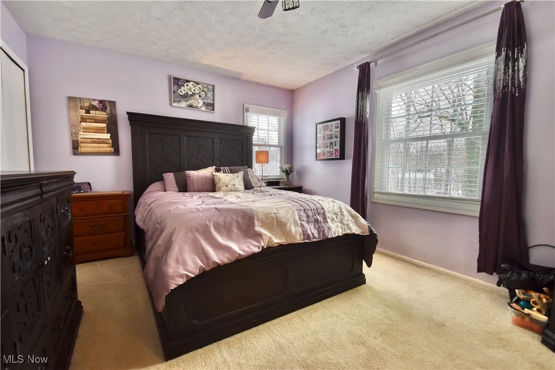 Bedroom with light colored carpet, a textured ceiling, and ceiling fan