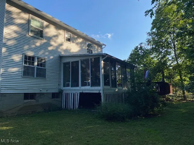 Back of property featuring a sunroom and a yard