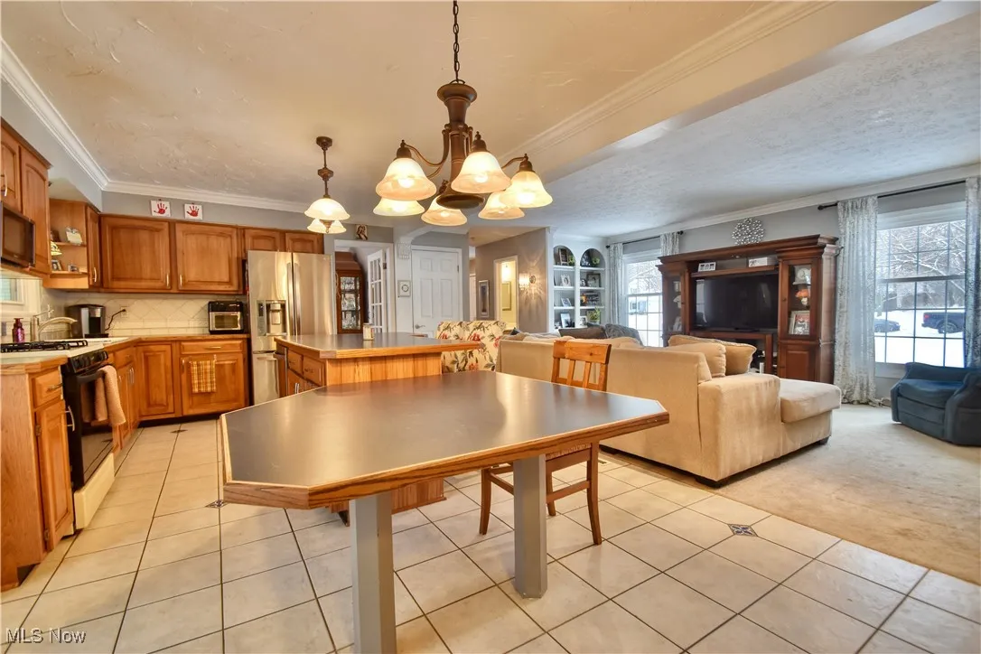 Dining space featuring ornamental molding, light tile patterned flooring, and a chandelier