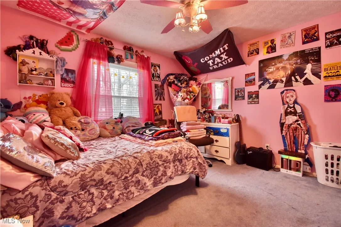Bedroom with a textured ceiling, carpet floors, and a ceiling fan