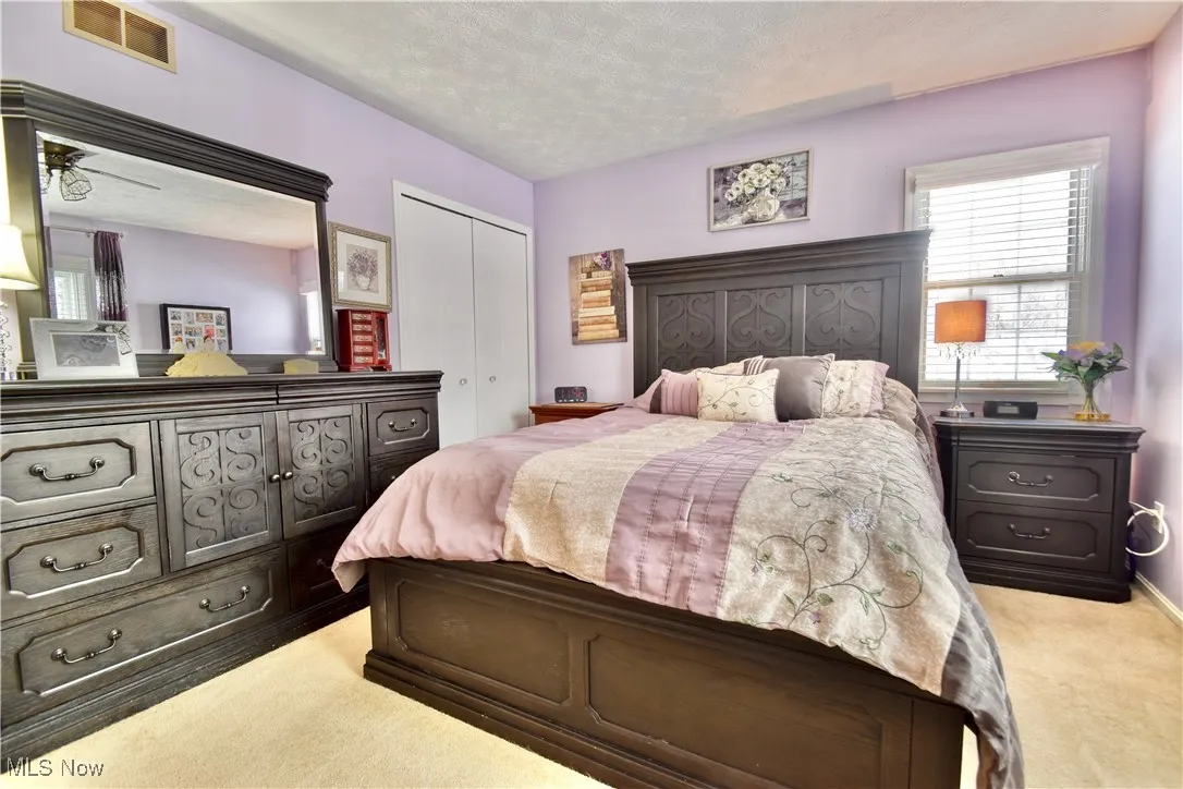 Bedroom with a textured ceiling, light colored carpet, and a closet