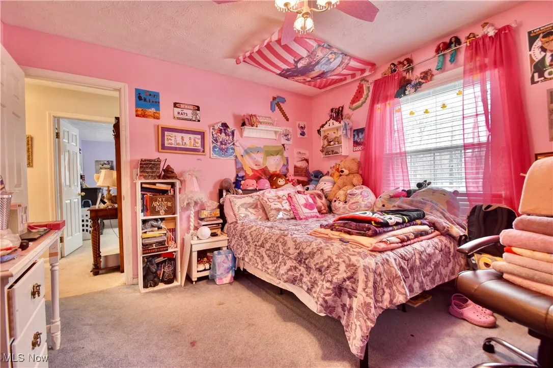 Bedroom featuring light carpet, a textured ceiling, and a ceiling fan