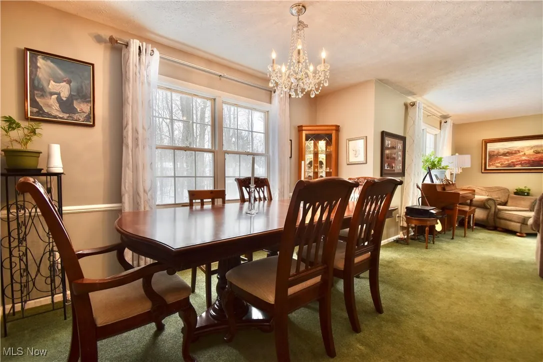 Carpeted dining room with a textured ceiling and a chandelier