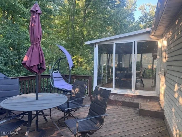 Deck featuring a sunroom and outdoor dining area