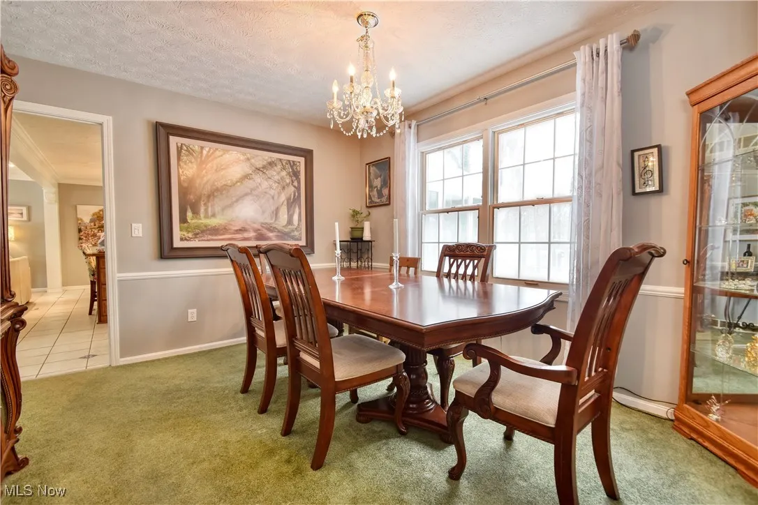 Dining space featuring a textured ceiling, a chandelier, and light carpet