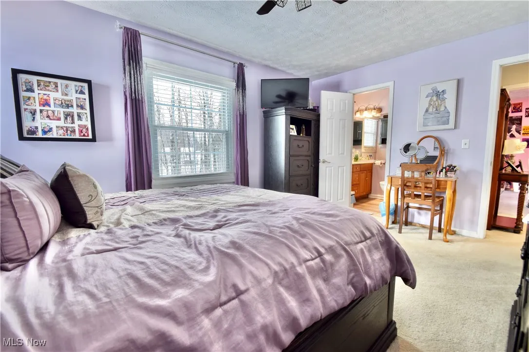 Bedroom with a textured ceiling, light colored carpet, and ceiling fan