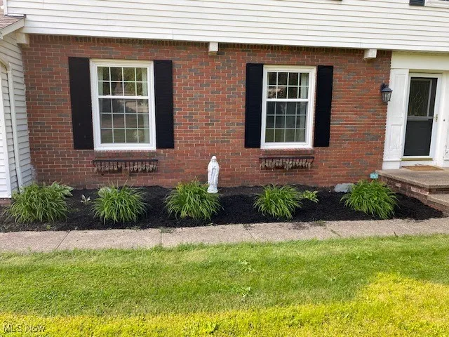 View of exterior entry with brick siding and a yard
