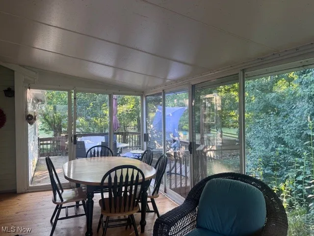 Sunroom with hardwood / wood-style floors, vaulted ceiling, and outdoor dining space