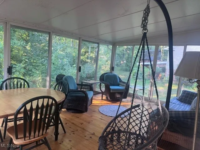 Sunroom / solarium with hardwood / wood-style flooring, vaulted ceiling, and expansive windows