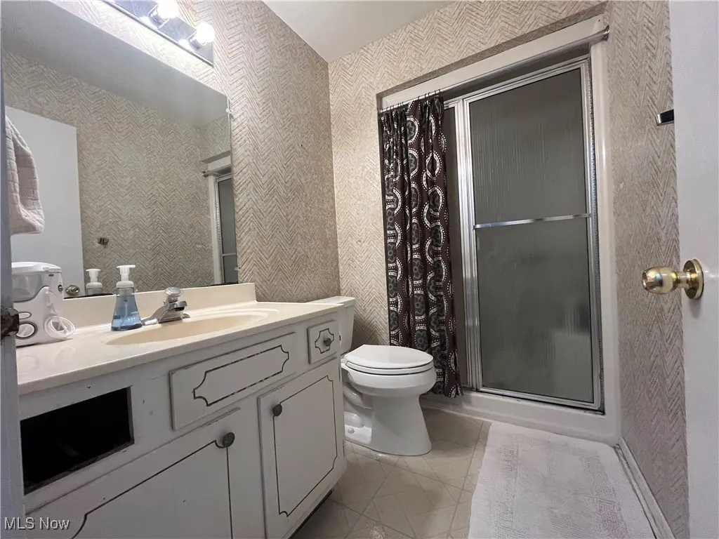 Full bath with a walk-in shower, vanity, and light tile patterned flooring