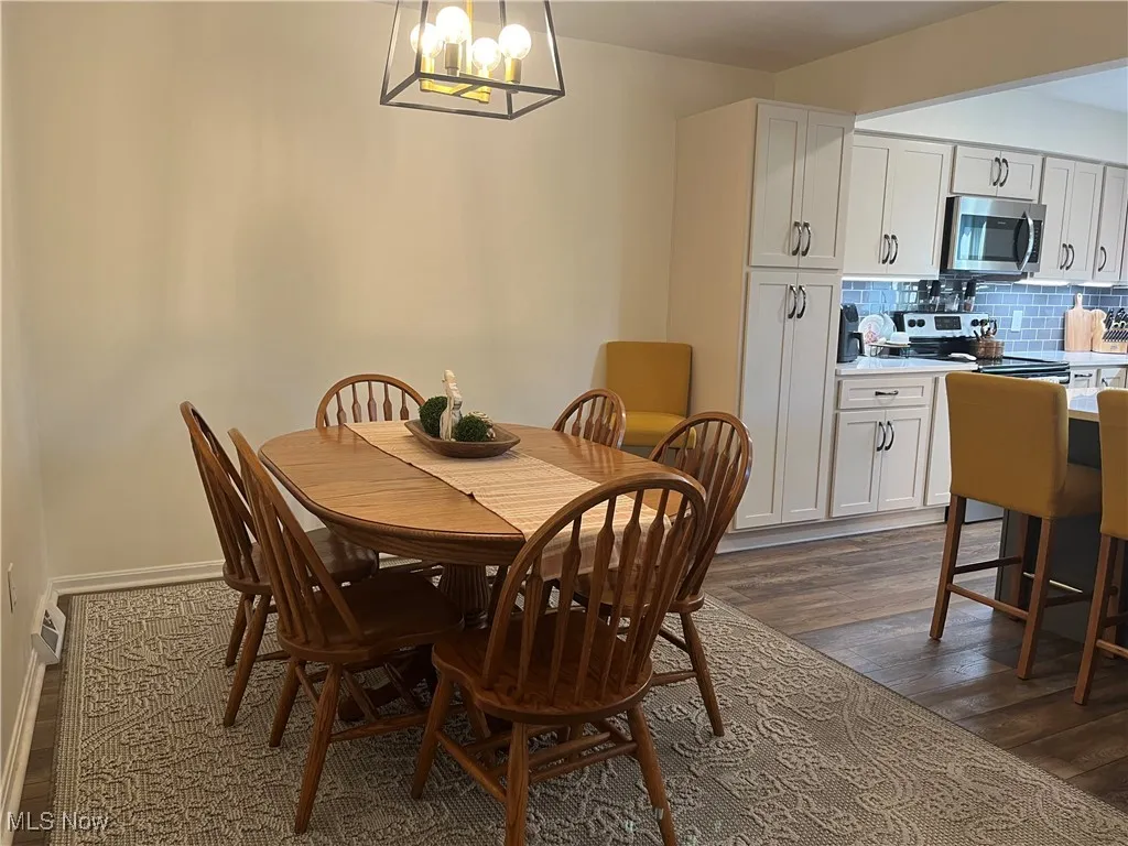 Dining space featuring dark wood-type flooring and a modern light fixture.