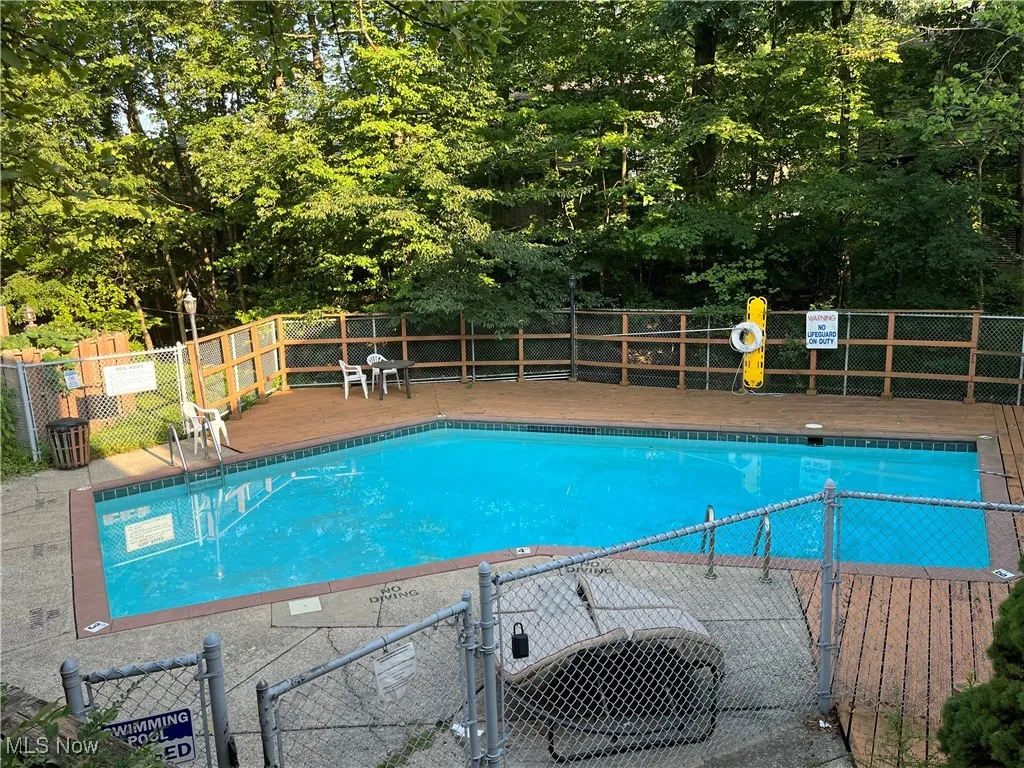 Community pool featuring a patio area and view of wooded area