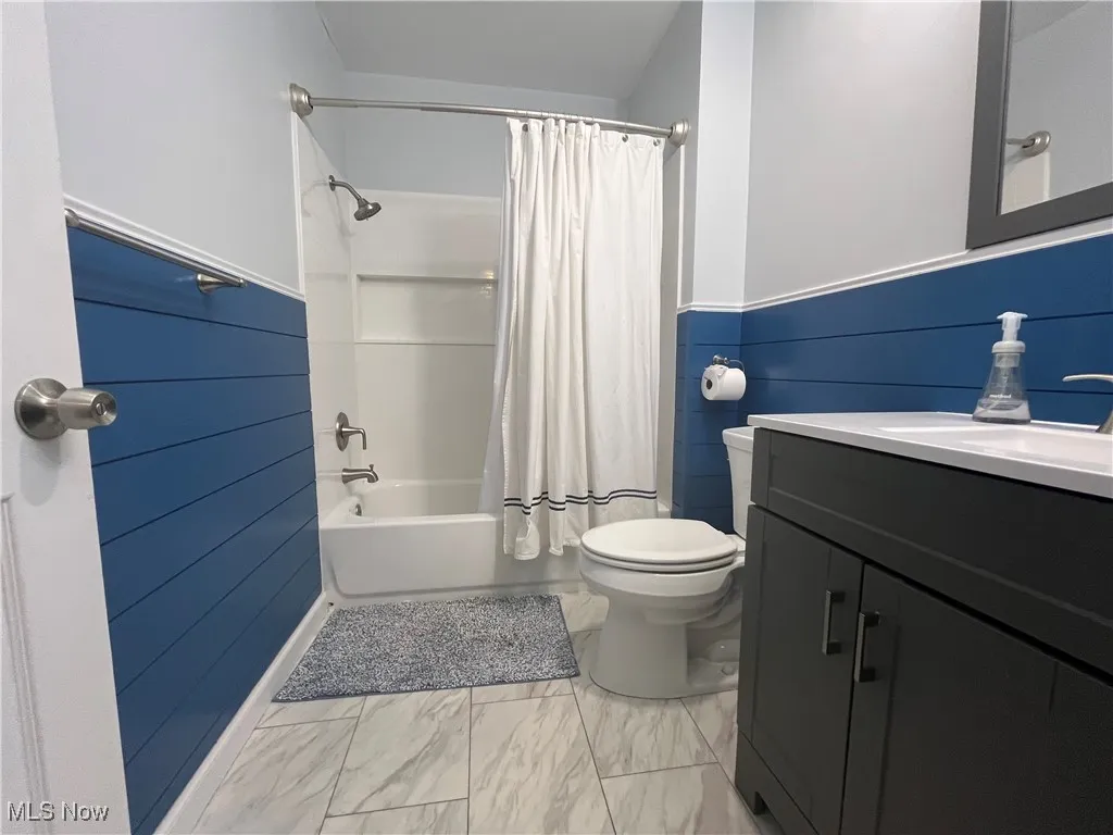 Second Full Bathroom upstairs features a shower / bath combo with shower curtain, vanity, light marble-like finish floors, and a wainscoted wall