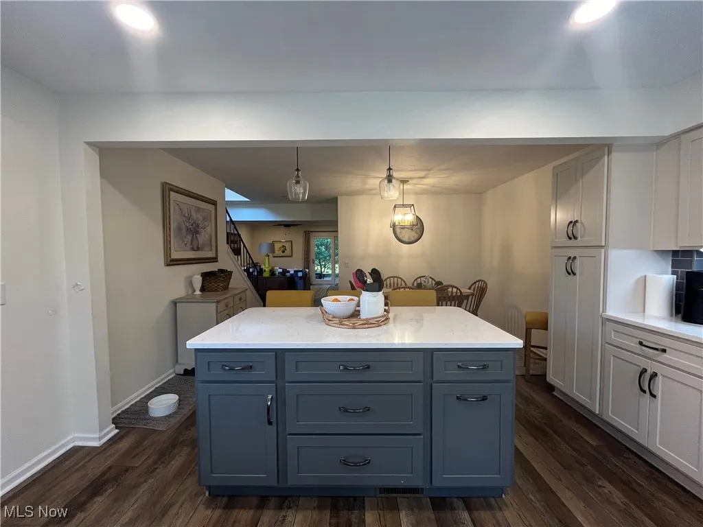 Kitchen with light stone counters, pendant lighting, dark wood-style floors, white cabinets, and recessed lighting