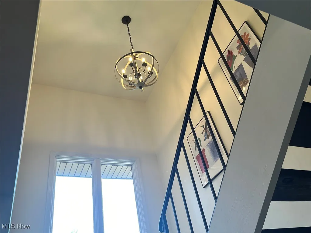 Detailed view of a chandelier and stairs going upstairs.