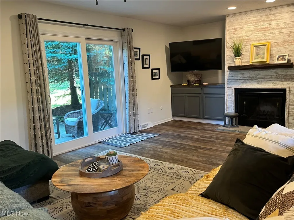 Living area with dark wood-style flooring, a large fireplace, and slider doors to the outside patio.