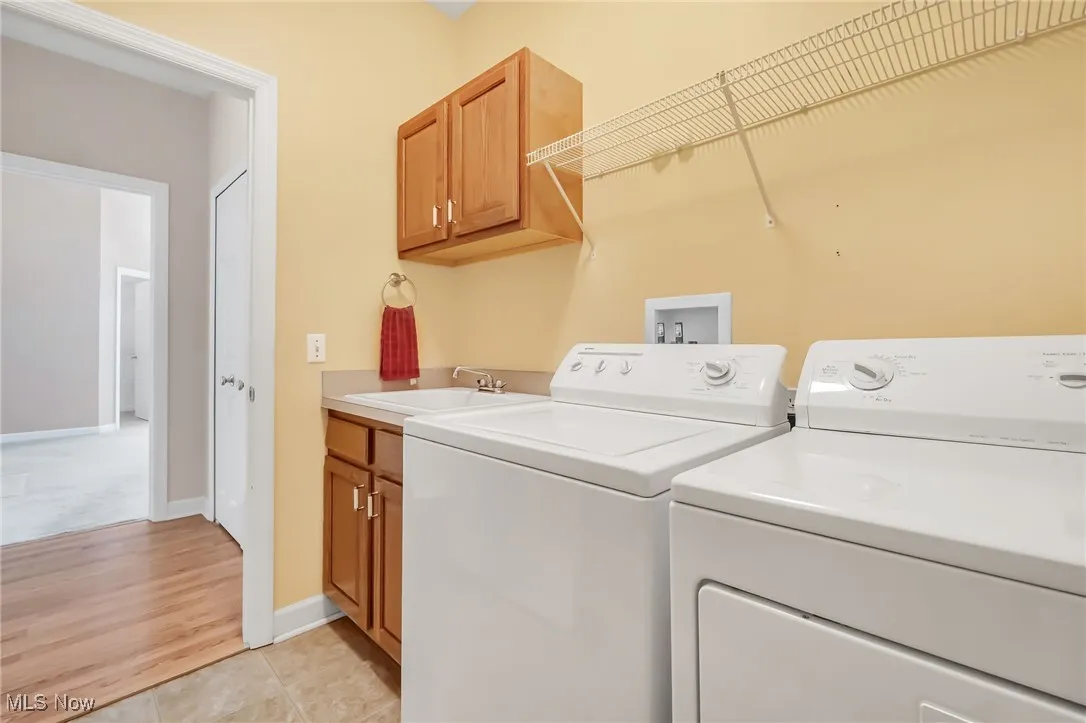 Laundry area with independent washer and dryer, cabinet space, and light tile patterned flooring