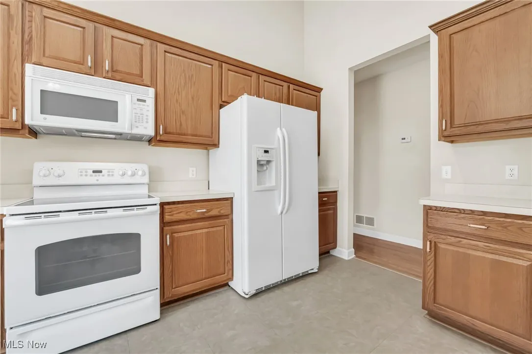 Kitchen with white appliances, light countertops, and brown cabinets