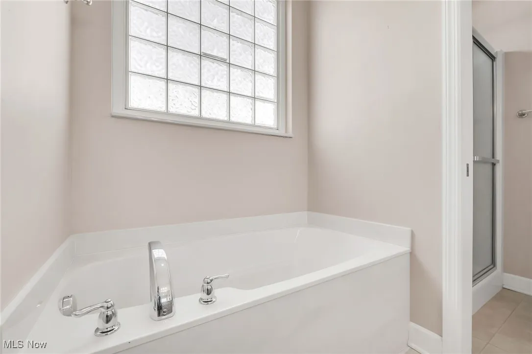Bathroom featuring a garden tub, a shower stall, and light tile patterned floors