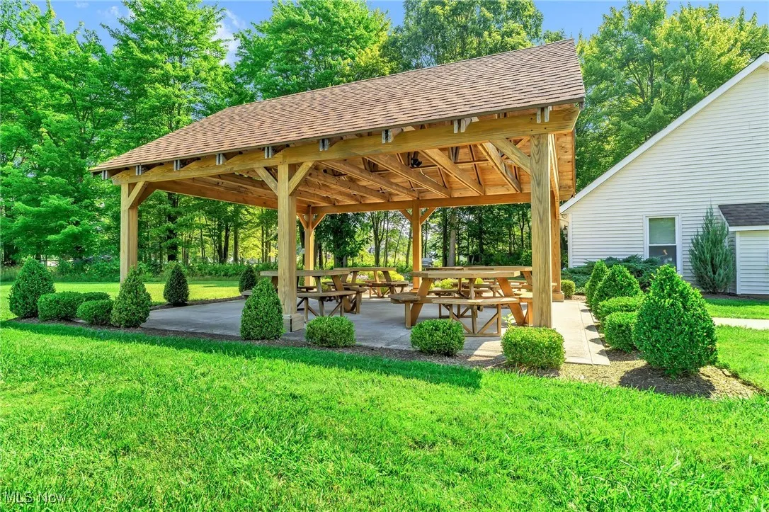 View of community featuring a patio, a lawn, and view of scattered trees