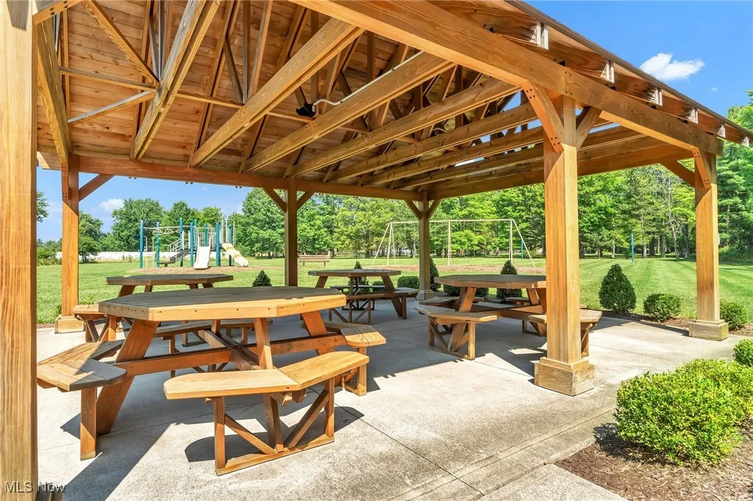 View of property's community featuring a lawn, a patio area, outdoor dining space, and view of scattered trees
