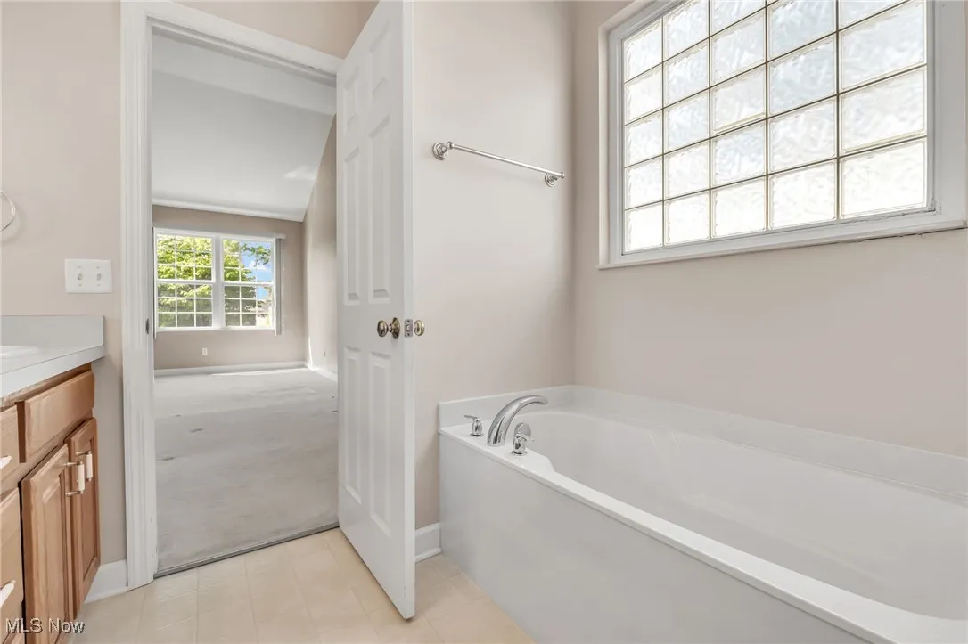 Full bathroom featuring vanity, a bath, and light tile patterned flooring