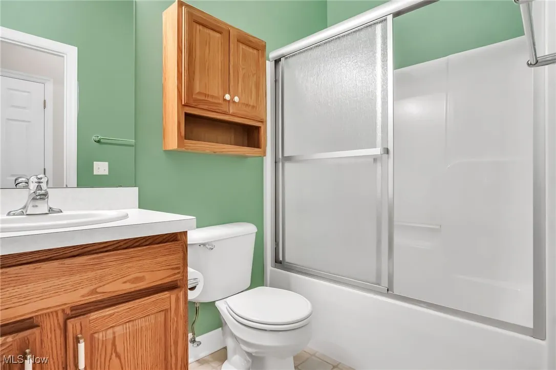 Bathroom with vanity, bath / shower combo with glass door, and light tile patterned floors
