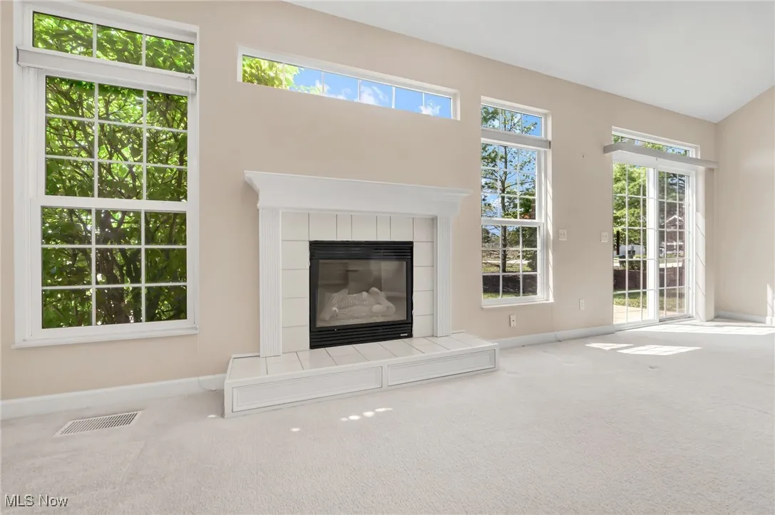 Unfurnished living room with a tiled fireplace and carpet flooring