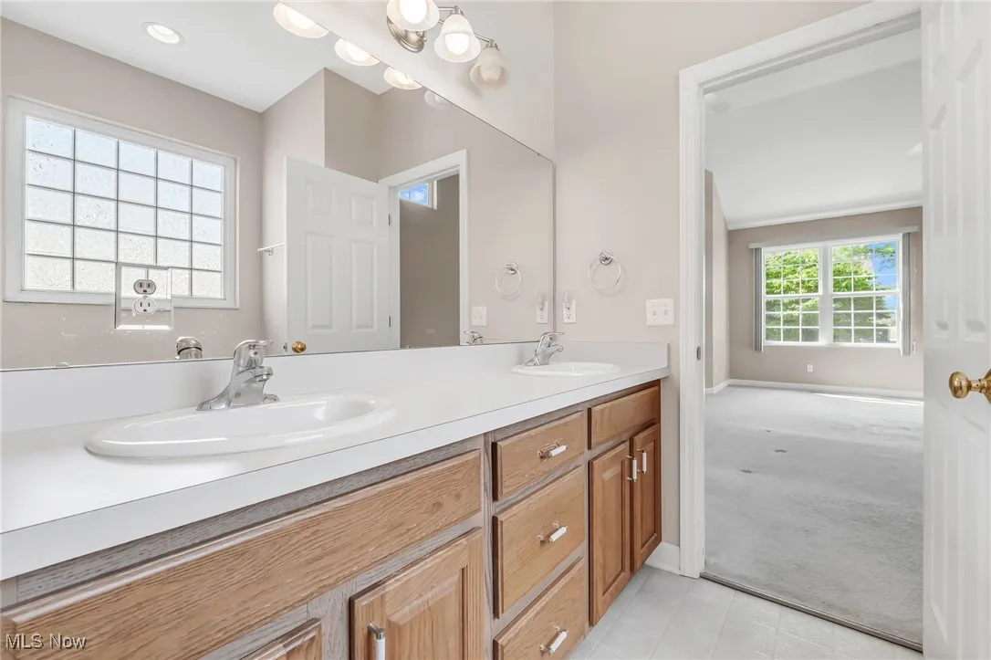 Bathroom featuring double vanity, plenty of natural light, and light tile patterned flooring