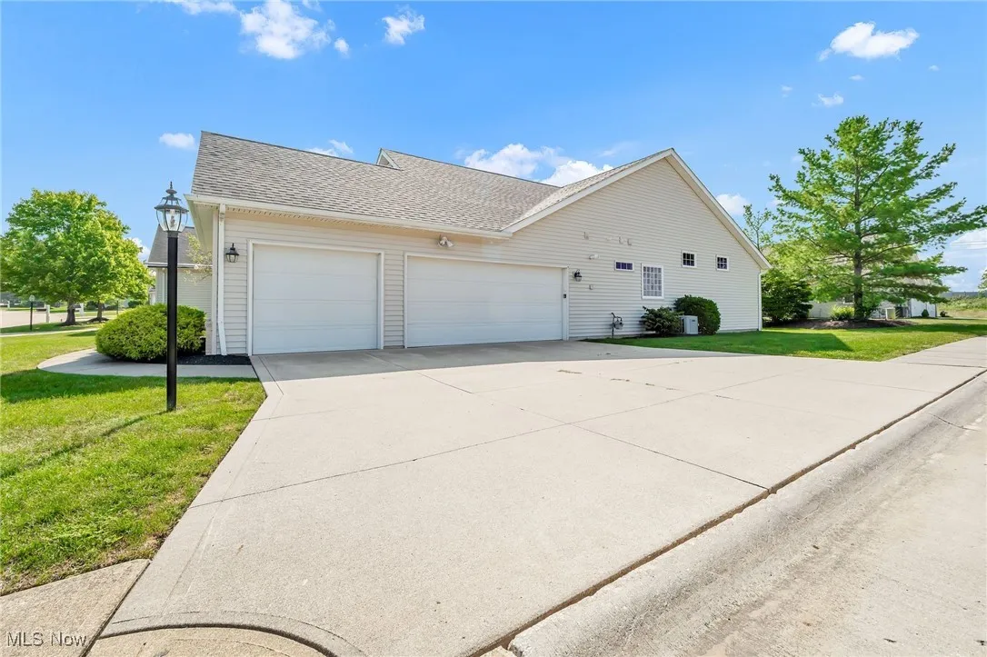 View of front of home with a front yard, a garage, roof with shingles, and concrete driveway