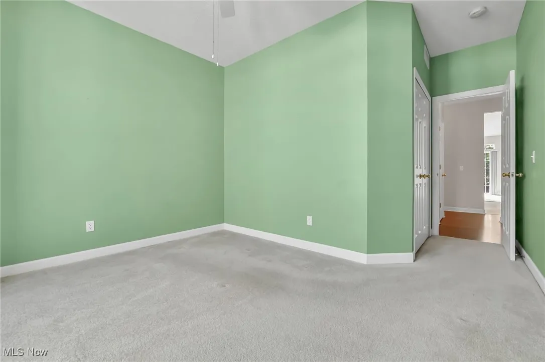 Carpeted empty room featuring baseboards and ceiling fan