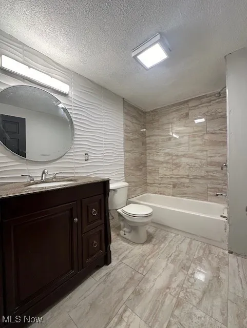 Full bath with vanity, bathing tub / shower combination, a textured ceiling, and light marble finish floors