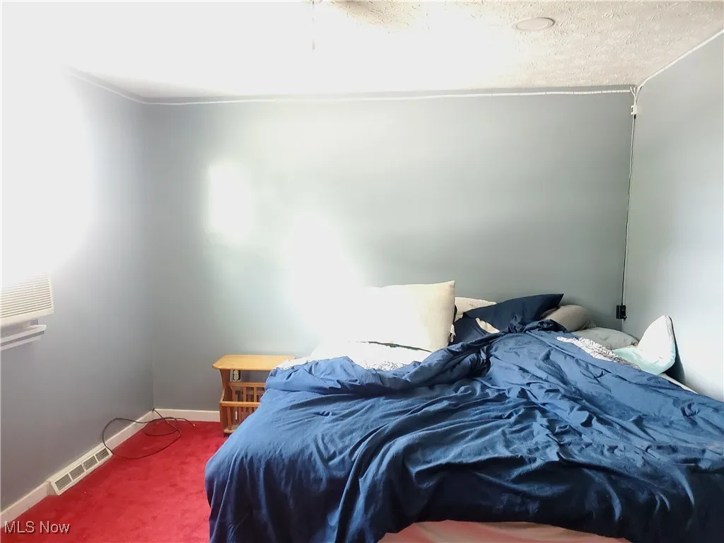 Carpeted bedroom with baseboards and a textured ceiling