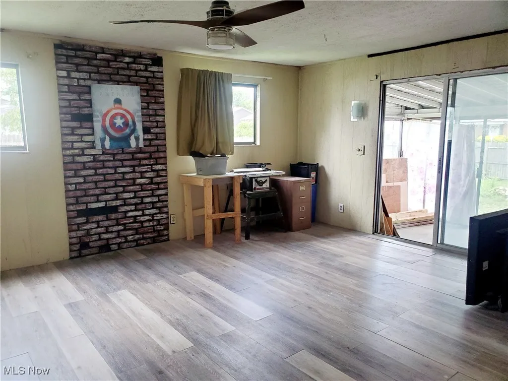 Office space with a textured ceiling, light wood finished floors, and a ceiling fan