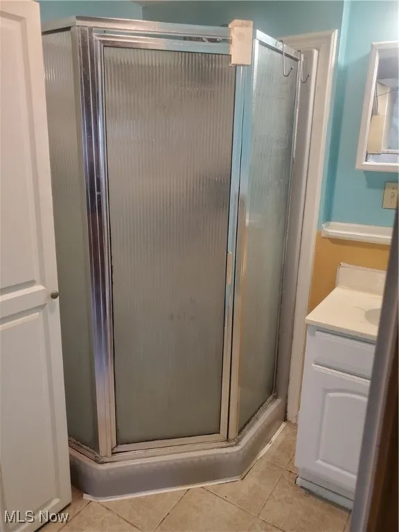 Bathroom with vanity, light tile patterned floors, and a stall shower