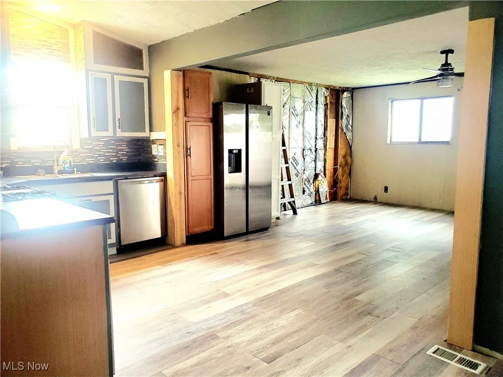 Kitchen with stainless steel appliances, brown cabinets, light wood-style floors, and decorative backsplash