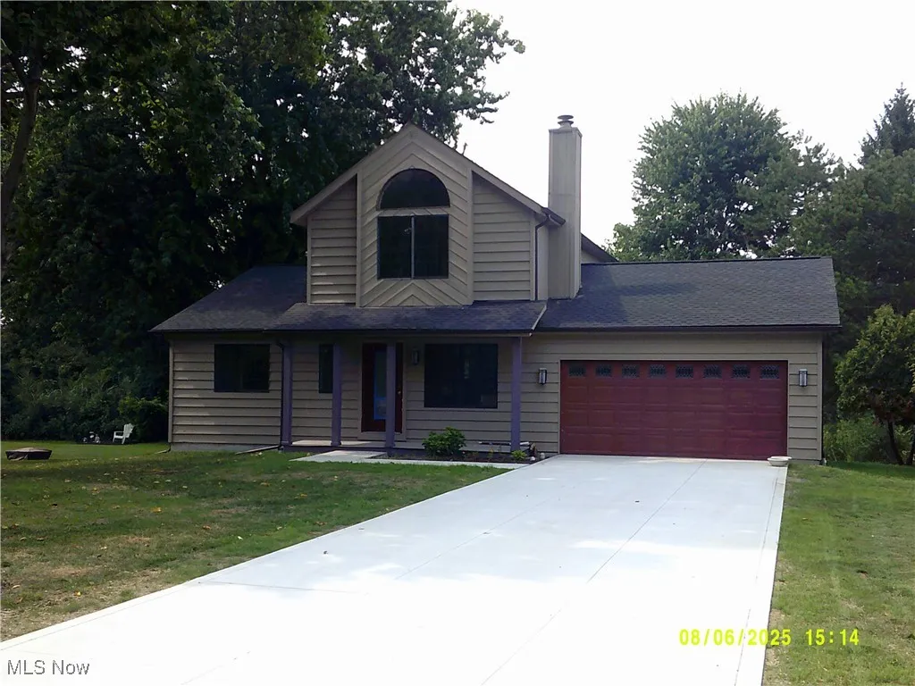 View of front facade featuring an attached garage, a chimney, concrete driveway, and a front lawn